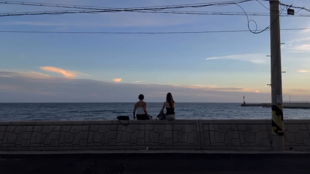 Two women and a lighthouse at sunset
