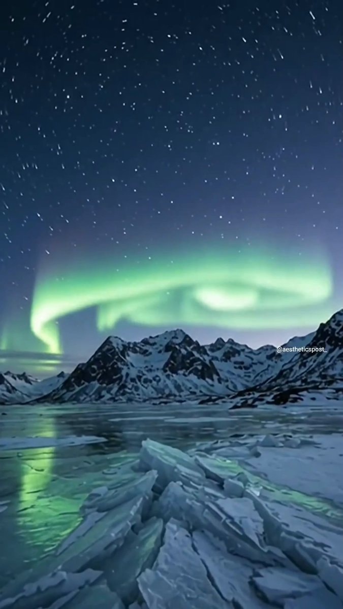 Green aurora over snowy mountains