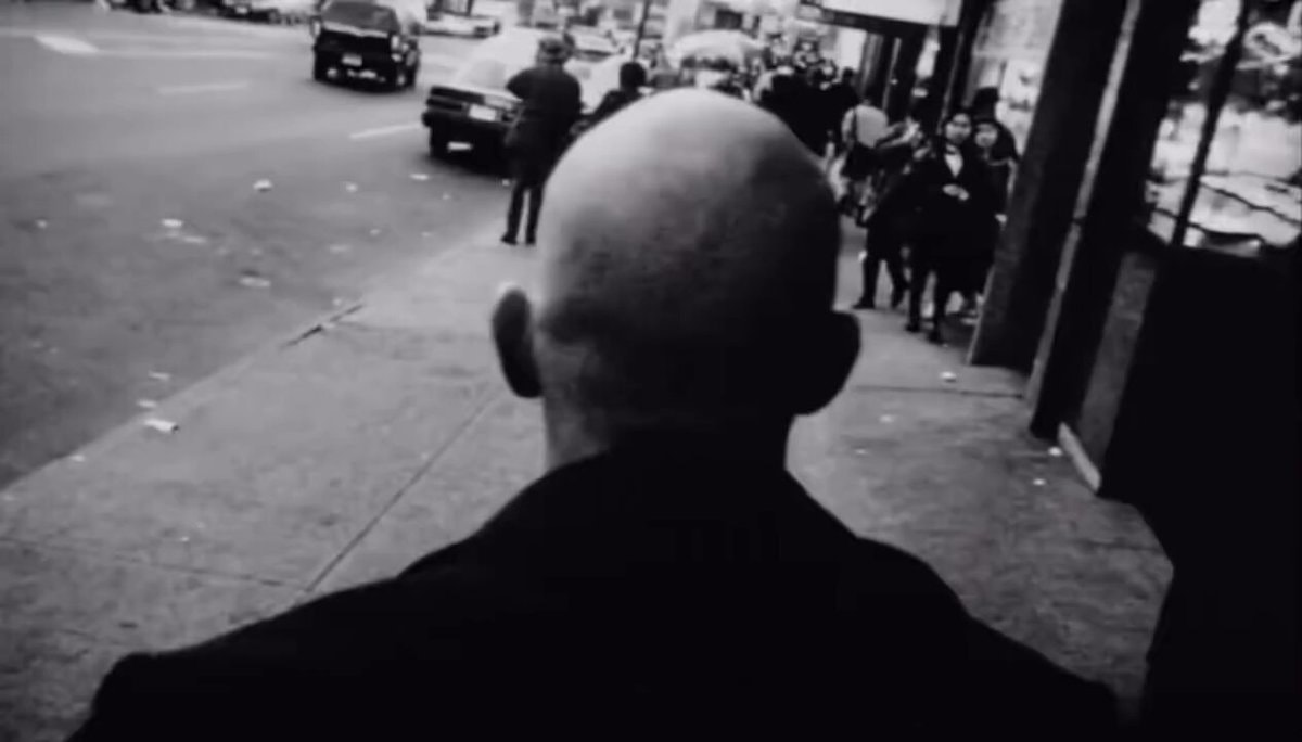 bald man walking urban sidewalk
