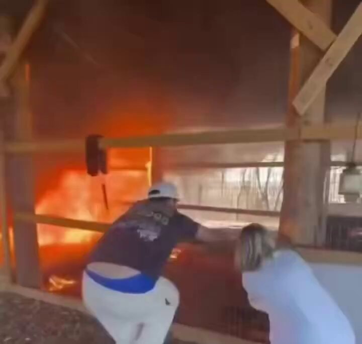 Two people reacting to a building engulfed in flames