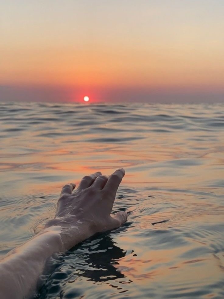 Hand reaching from ocean at sunset (photo 2 of 2)