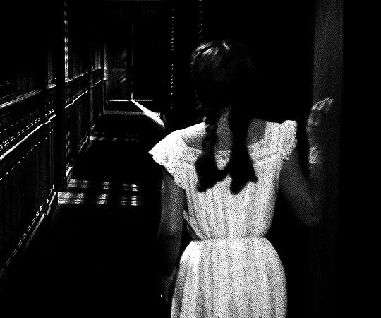 young person walking down dark hallway