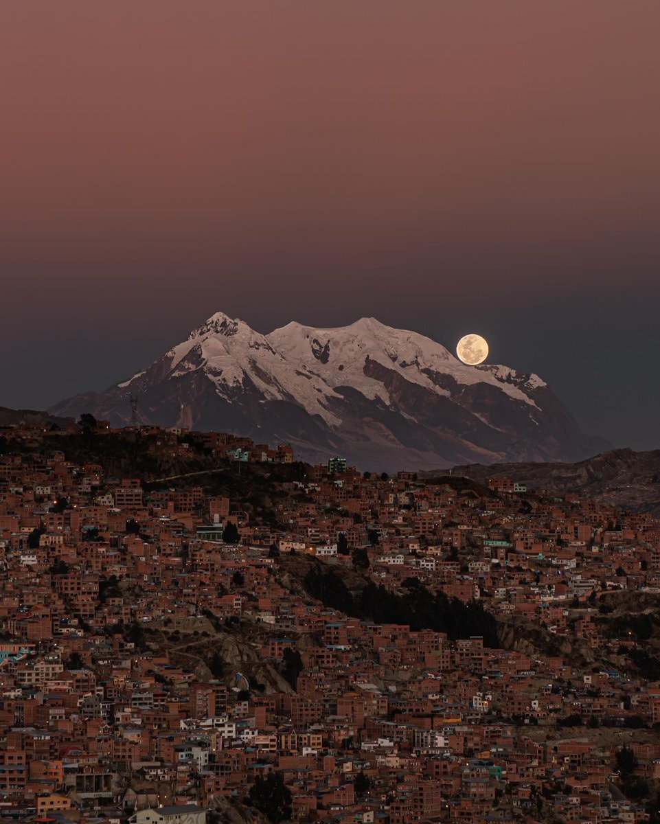 Cityscape with full moon behind mountains
