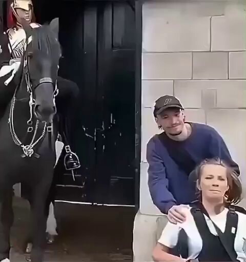 Soldier on horseback helps woman pose
