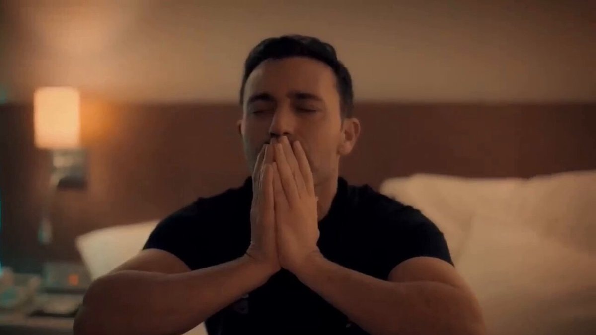 Man praying in bedroom with black t-shirt