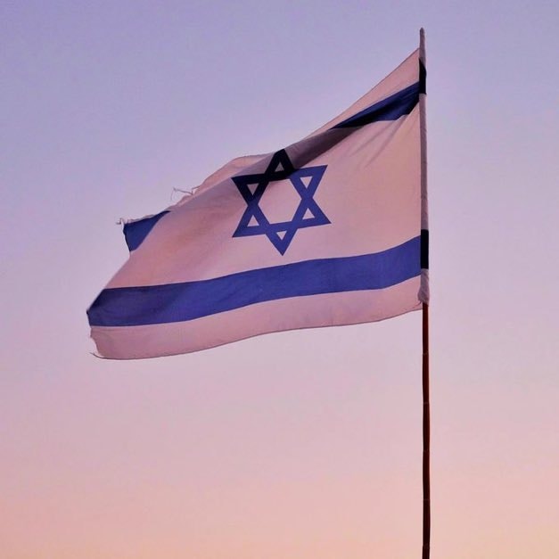 Israeli flag waving against purple sky