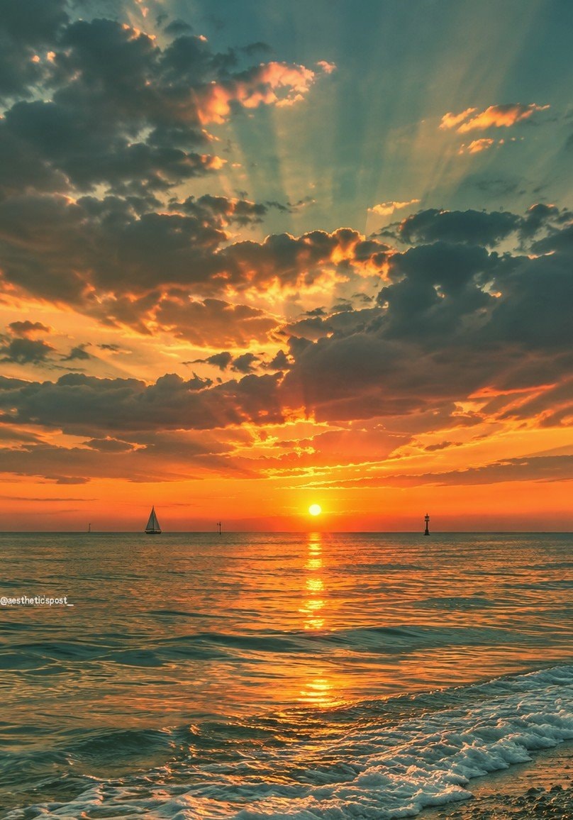 sailboat at sunset with lighthouse