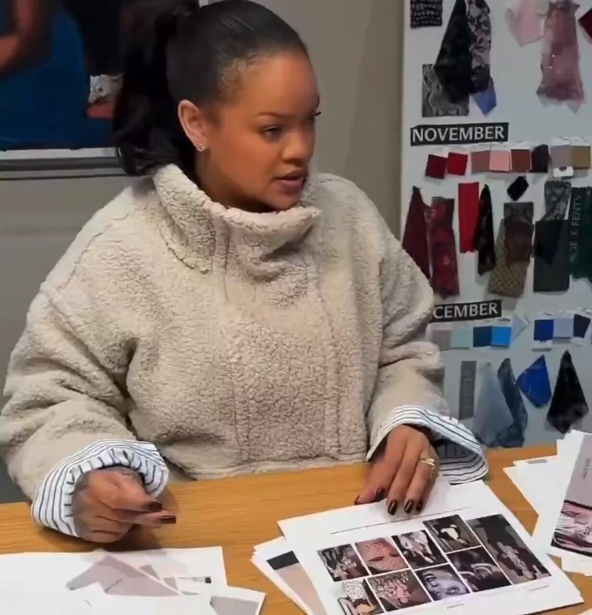 Rihanna seated at table with design materials