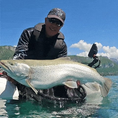 Man holding spotted coelacanth on boat