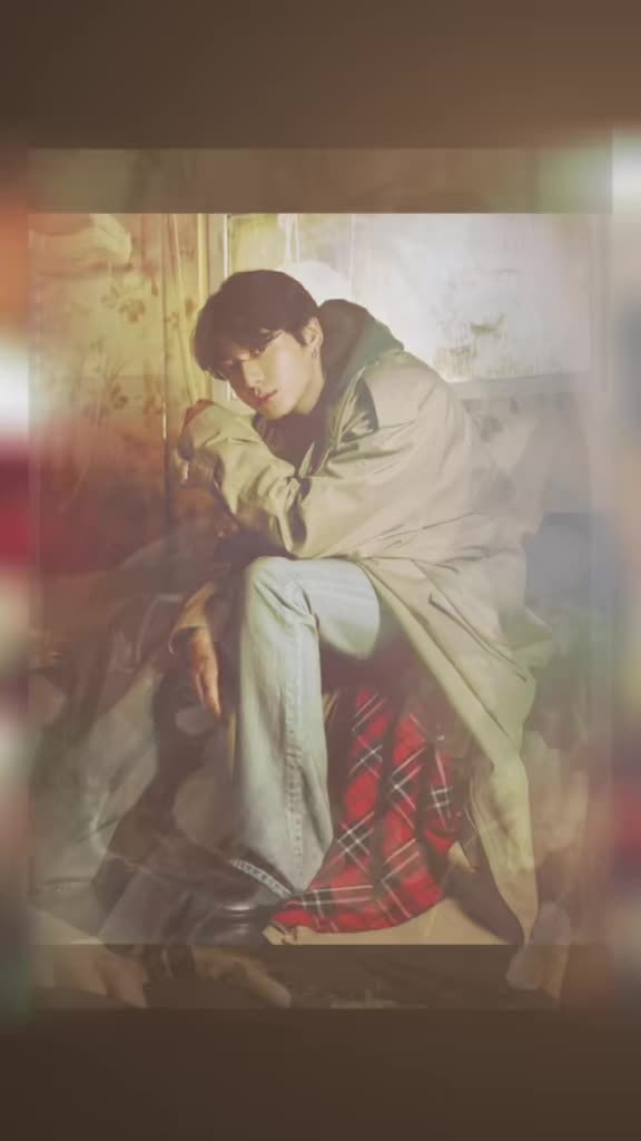 young man seated in trench coat