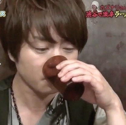 Man drinking from cup with Kazunari-san Shibuya text