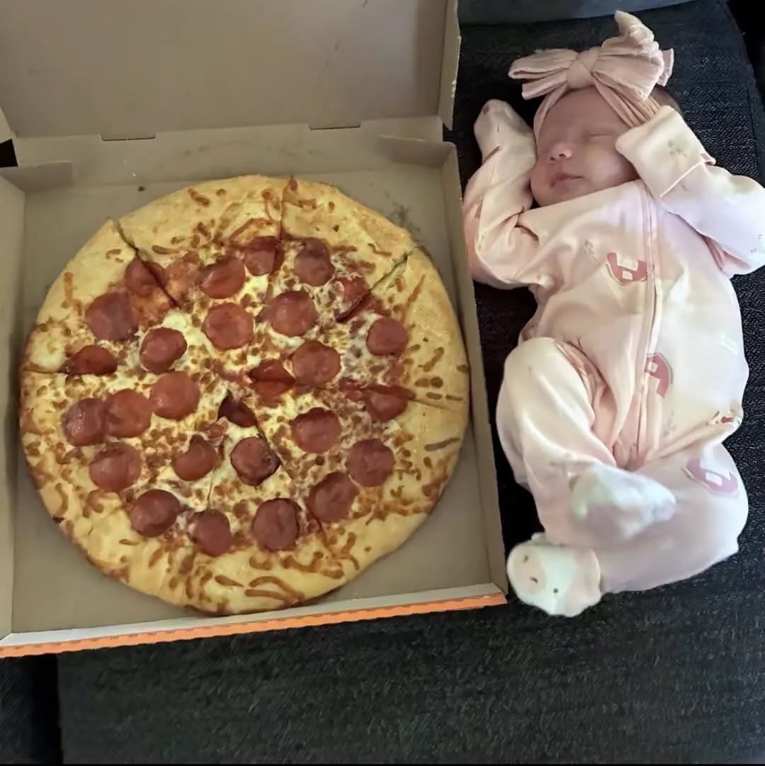 baby sleeping next to pizza