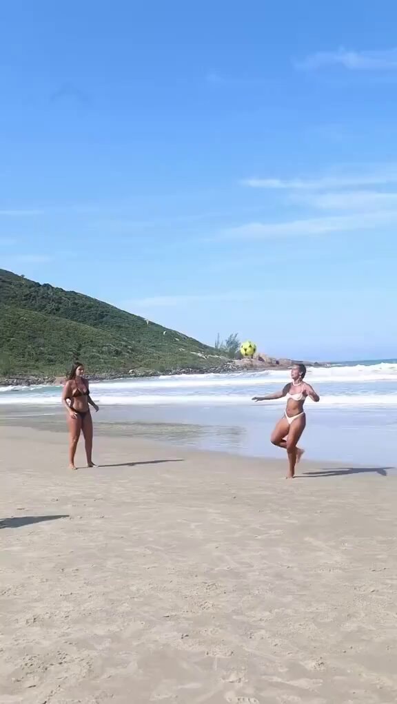Women playing soccer on beach