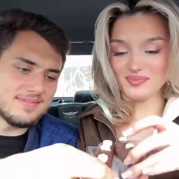 Young couple sharing donut in car