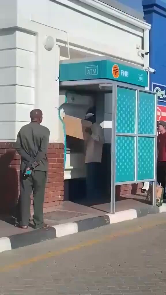 Person with box at FNB ATM booth