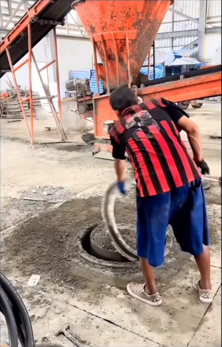 Factory worker pours concrete ring
