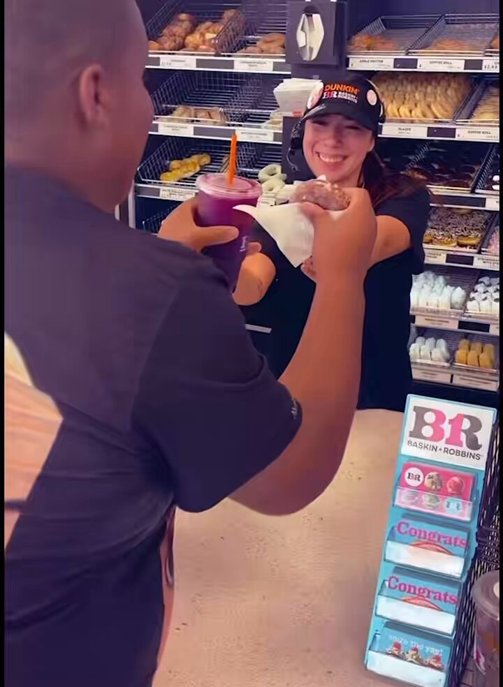 Dunkin employee handing donut