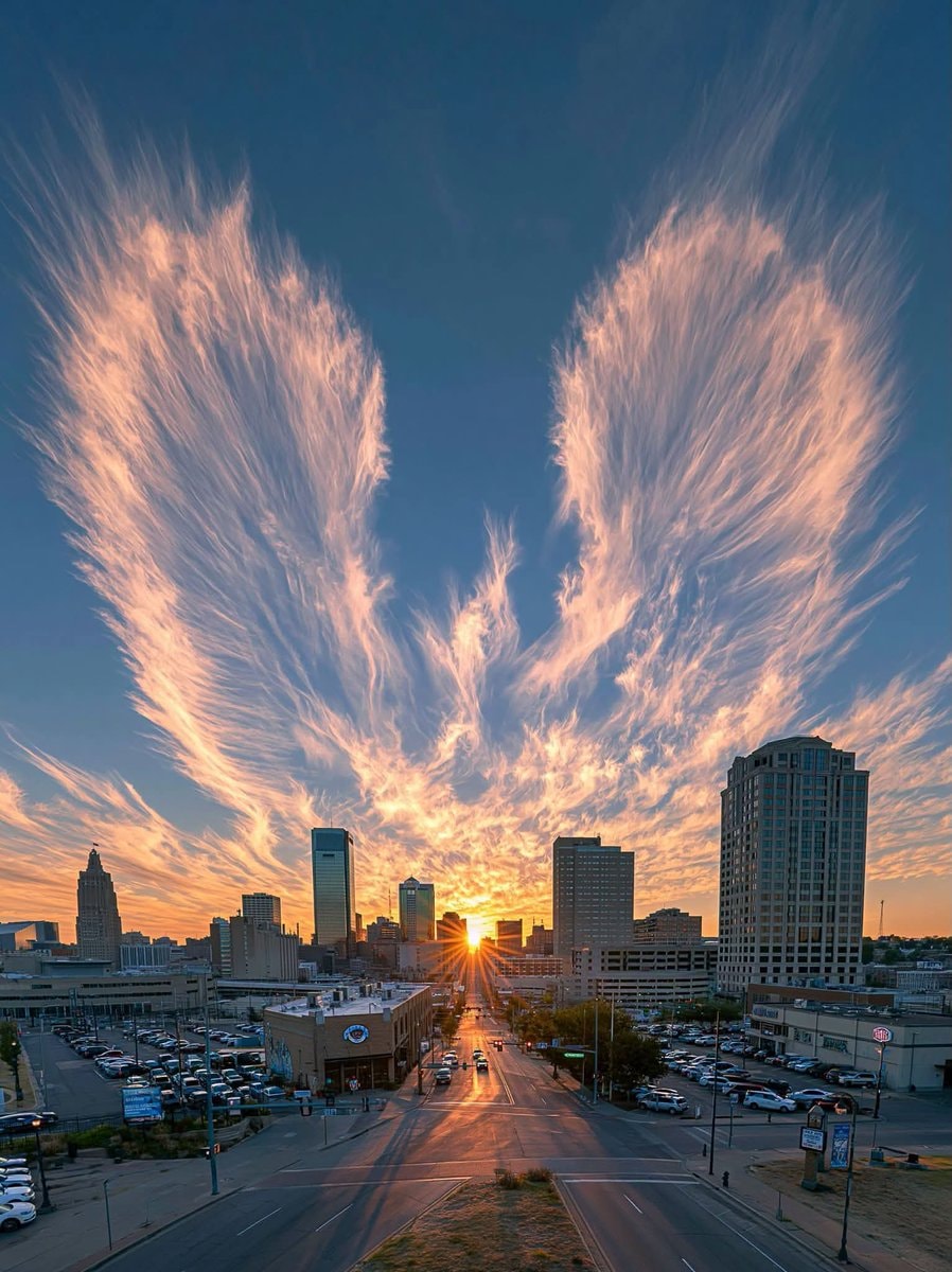 Giant wing clouds over city at sunset