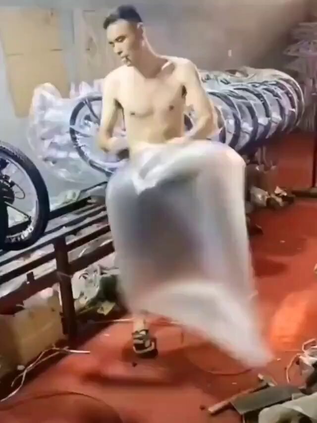 Man wrapping large object in plastic workshop