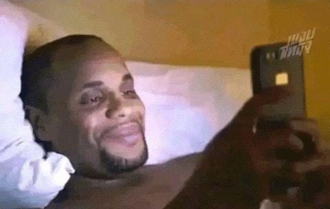 Man in bed amused with phone GIF