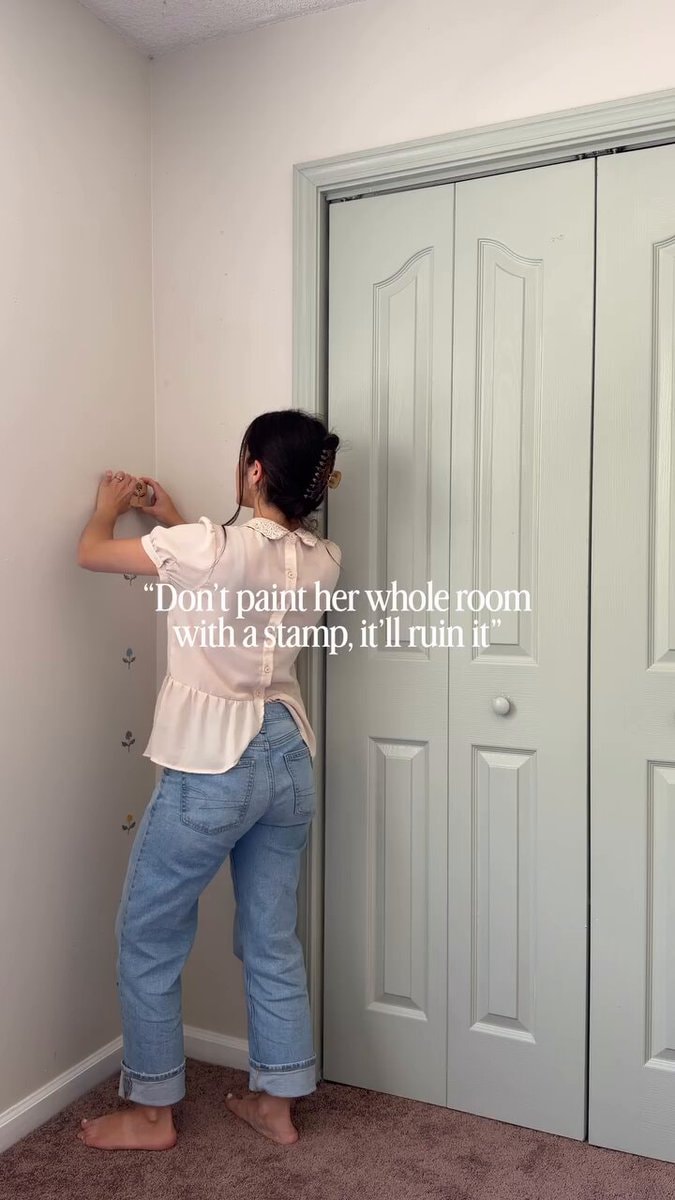 woman applying floral decal to wall