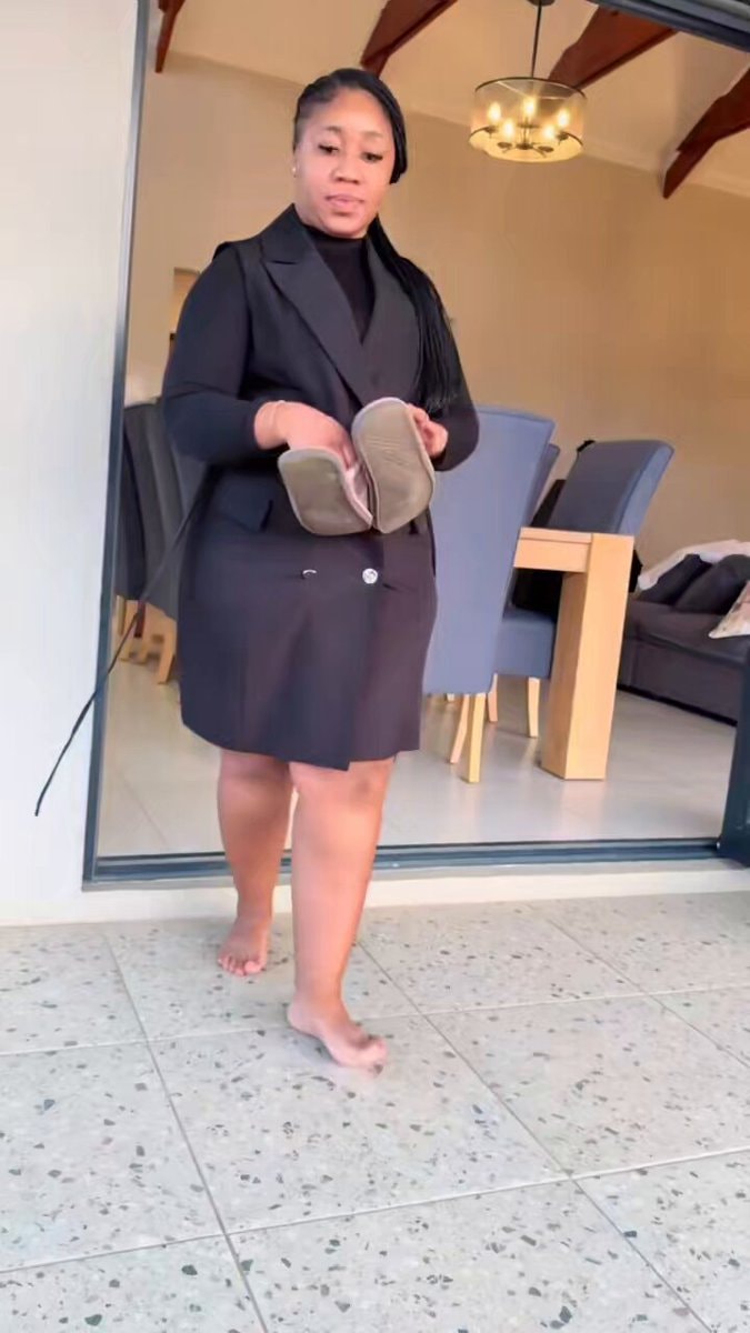 woman in blazer dress holding pink slippers