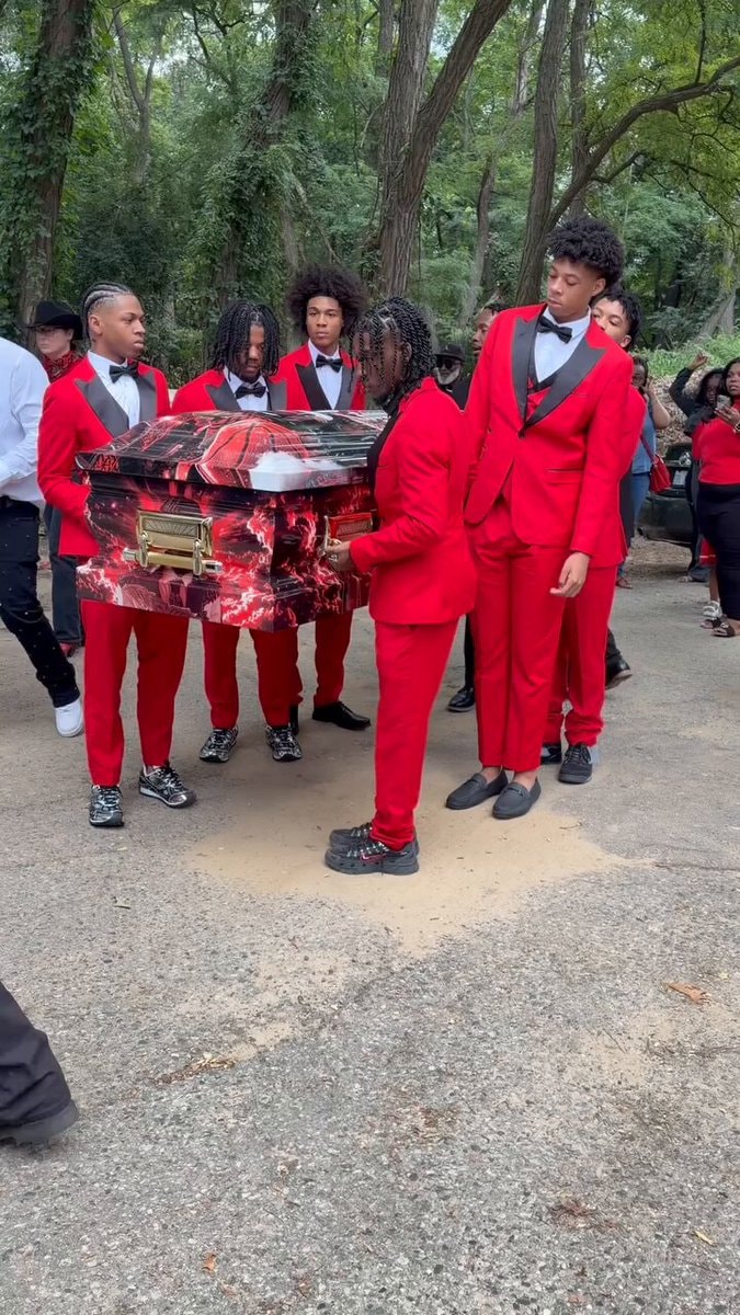 men in red suits carrying casket