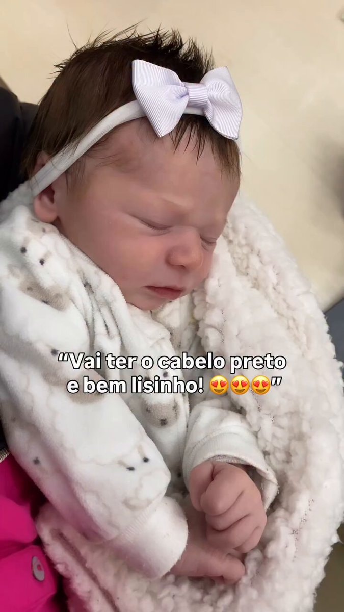 Newborn baby with dark hair swaddled in animal face blanket
