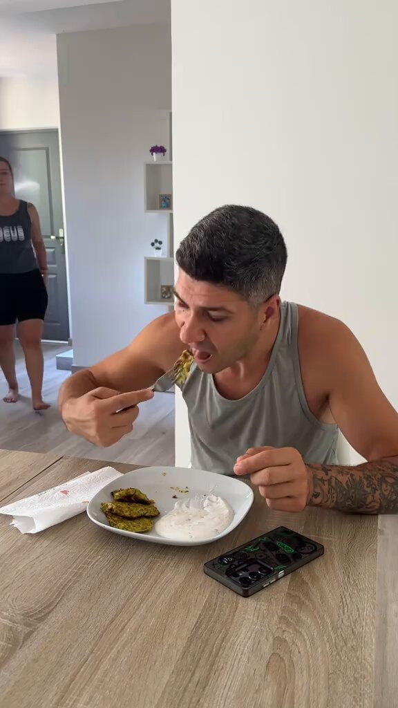 man eating green patties and white dip