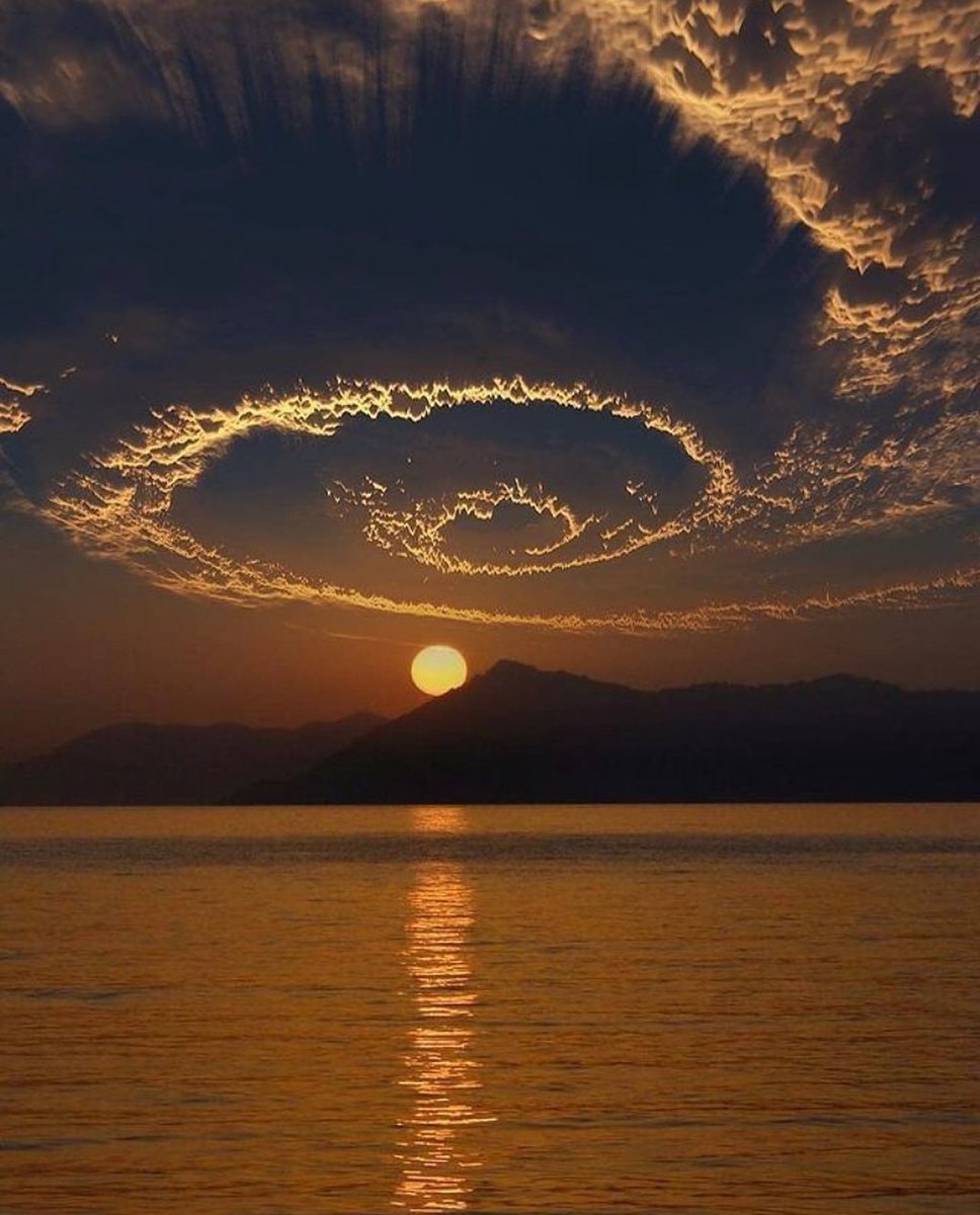 Sunset over mountains with swirling clouds