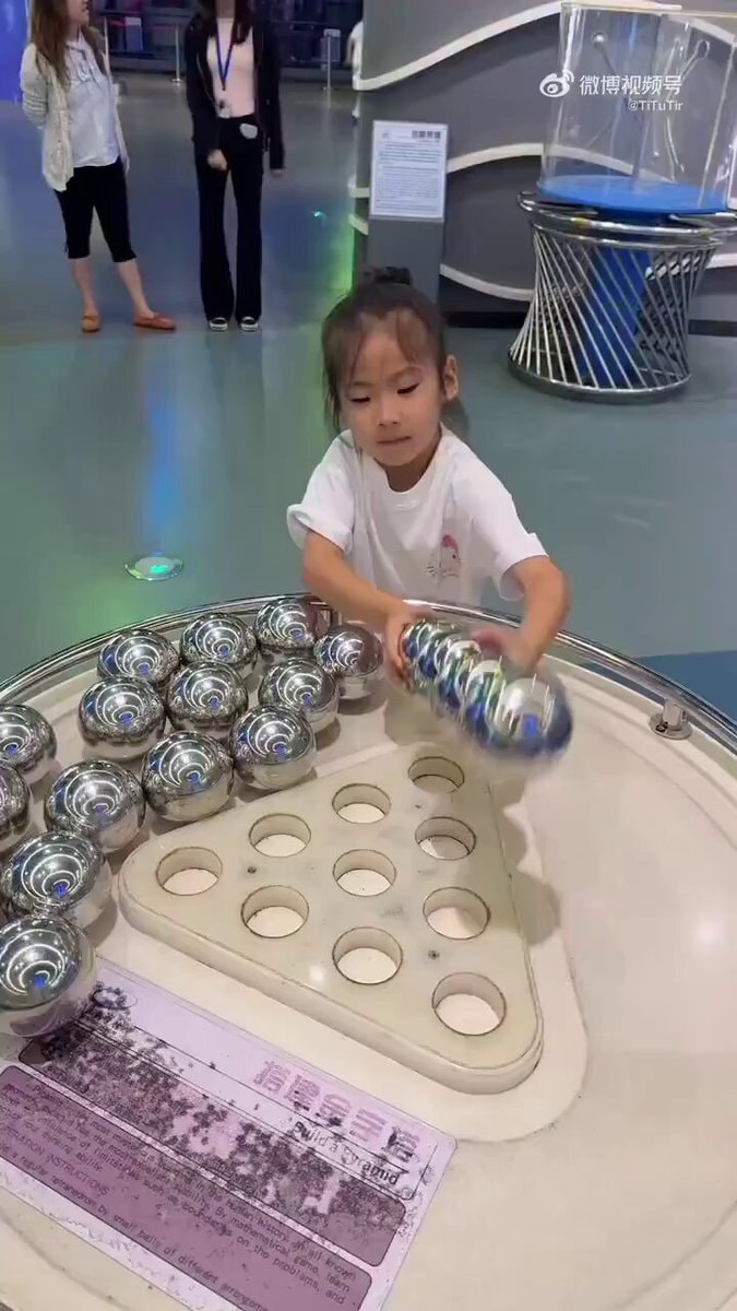 Girl builds pyramid with metal balls